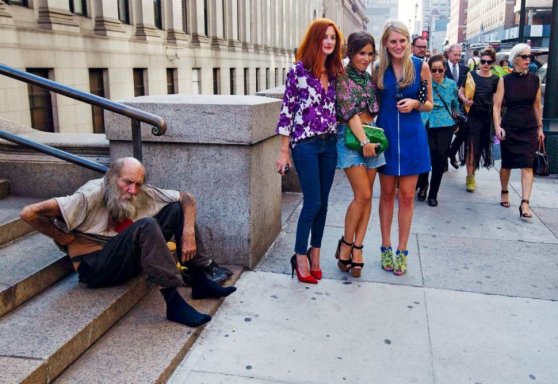 Three young women from the New York Fashion Week pose next to a homeless man. [2012]